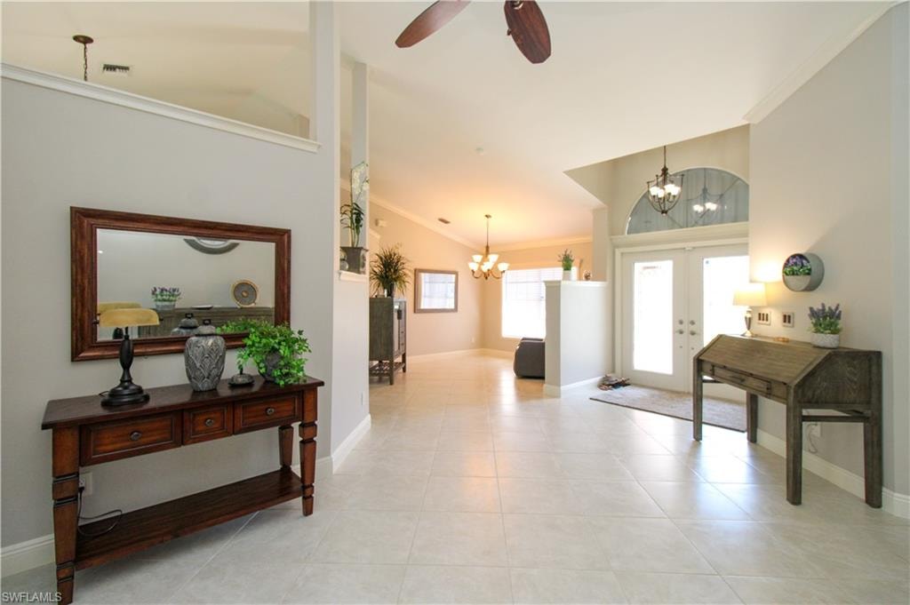 Foyer entrance featuring visible vents, baseboards, light tile patterned floors, ceiling fan with notable chandelier, and french doors