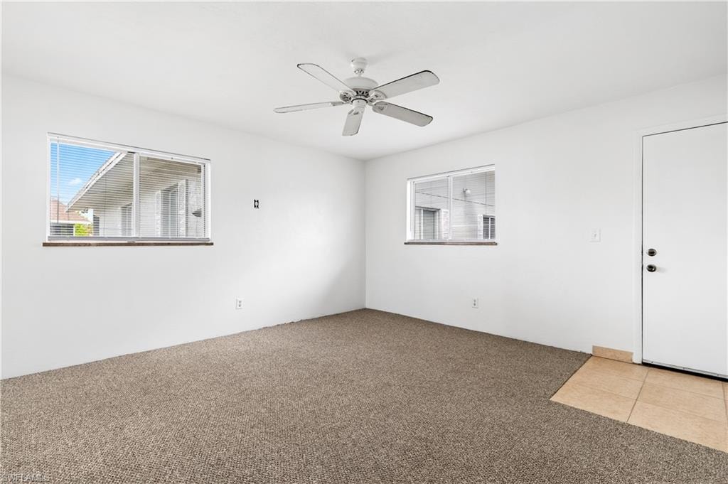 Tiled spare room featuring carpet floors and ceiling fan