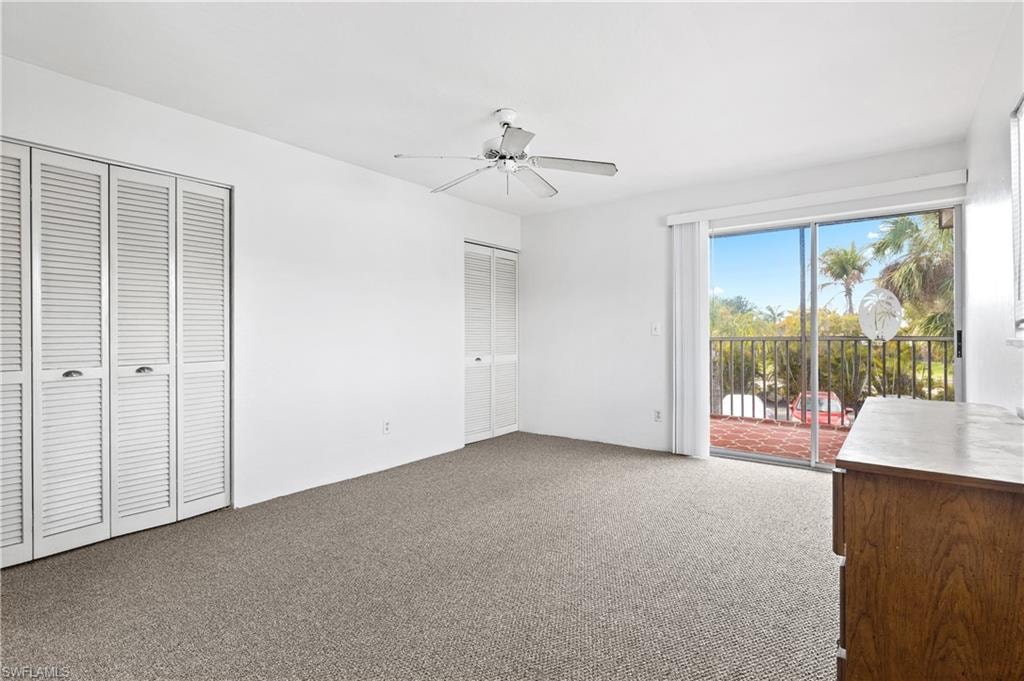 Unfurnished bedroom featuring multiple closets, access to outside, light carpet, and a ceiling fan