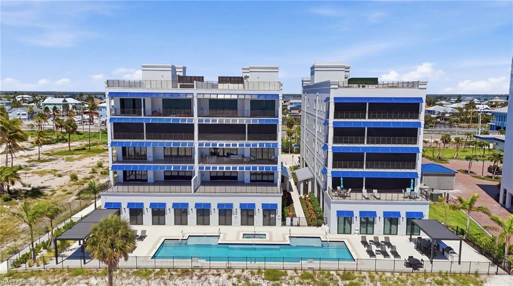 Multi-story building featuring private balconies with awnings, ground-level awnings, and a concrete pool deck with a rectangular pool and integrated spa - Virtually Edited Image