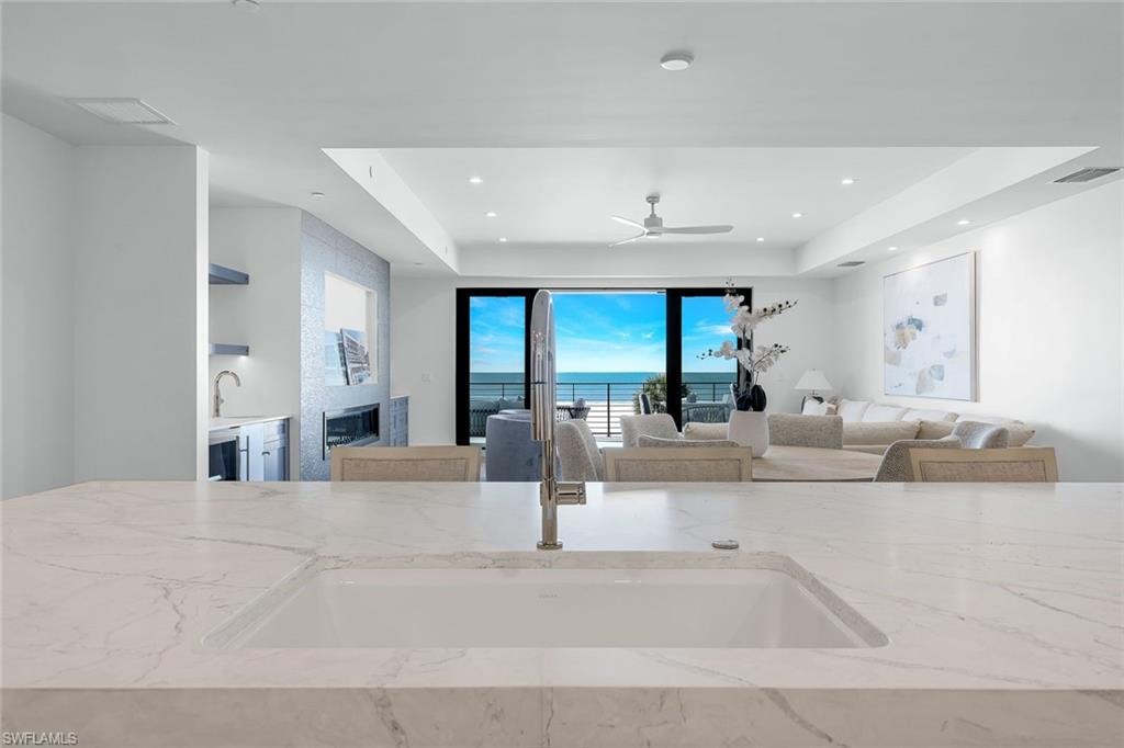 Kitchen with light stone countertops, ceiling fan, a tray ceiling, and recessed lighting