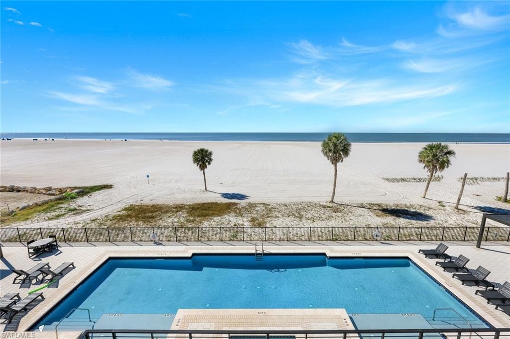 Community pool featuring a patio area and view of water and beach
