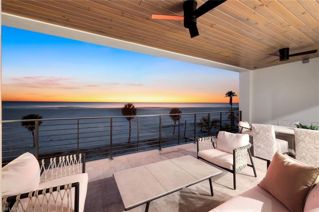 Balcony at dusk with a patio area, a ceiling fan, an outdoor lounge area, and a water view