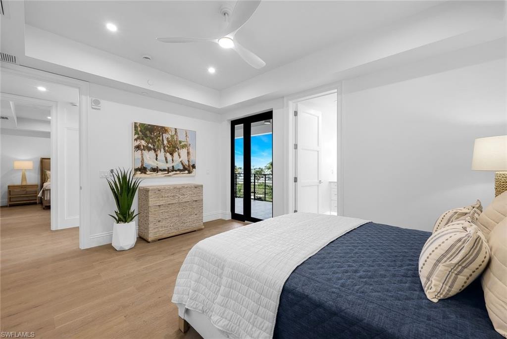 Bedroom featuring a tray ceiling, wood finished floors, access to outside, recessed lighting, and a ceiling fan