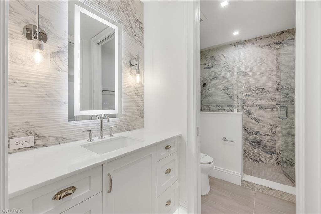 Bathroom featuring vanity, a shower stall, tile walls, and recessed lighting