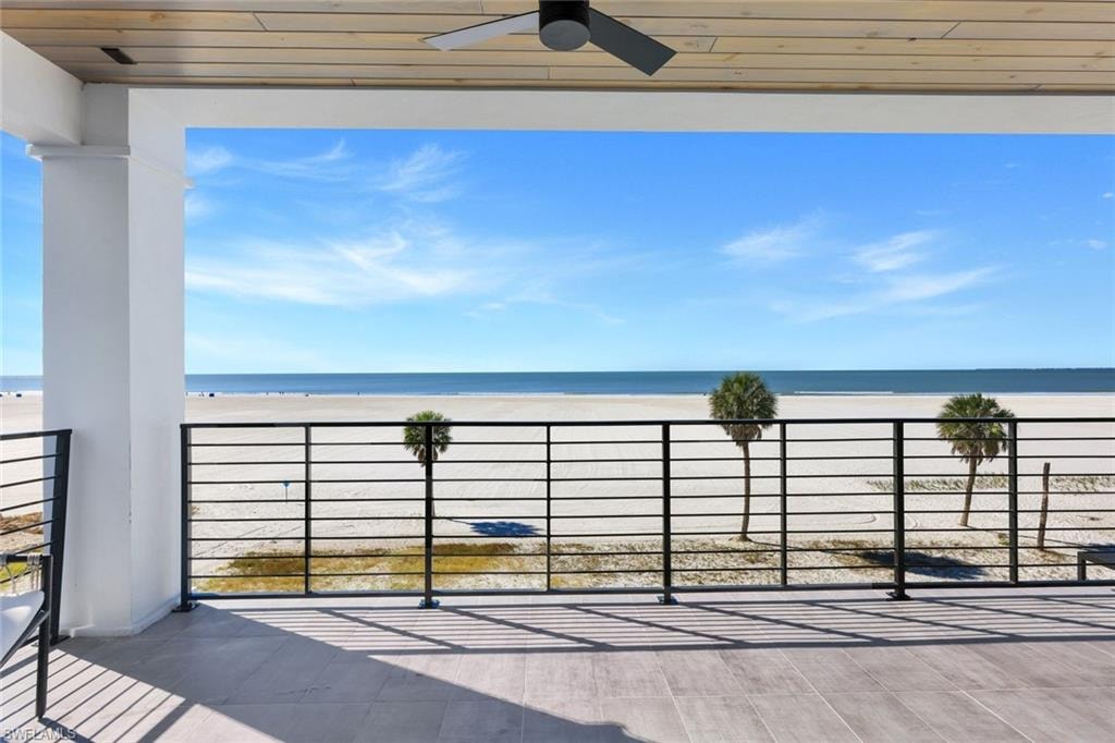 Balcony with ceiling fan and view of water and beach
