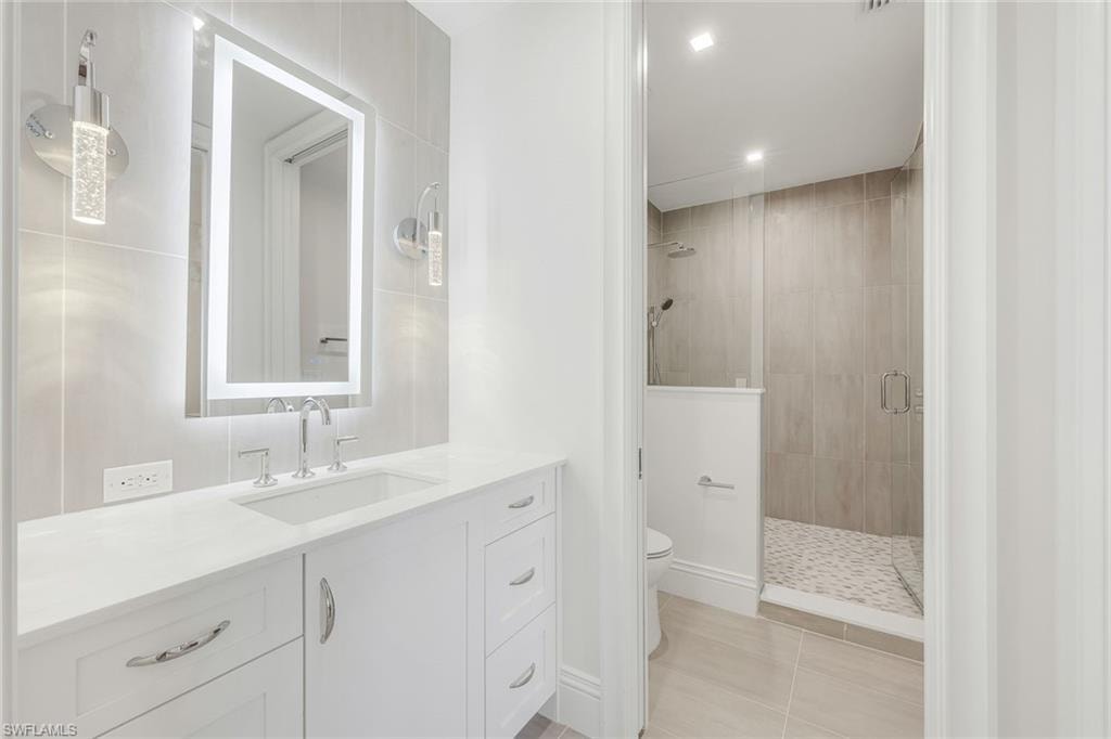 Bathroom featuring vanity, a stall shower, recessed lighting, and light tile patterned flooring