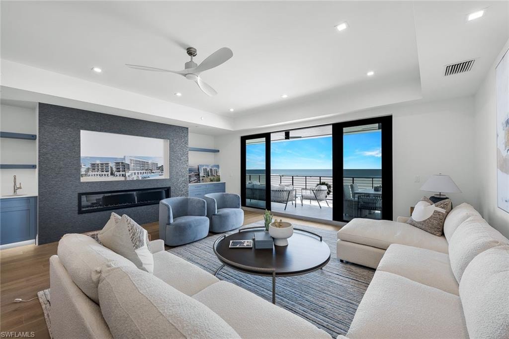 Living area featuring ceiling fan, wood finished floors, a water view, built in features, and recessed lighting