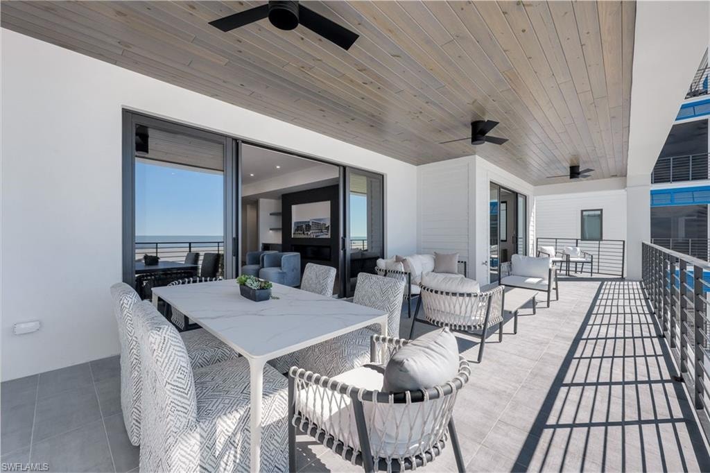 View of patio with ceiling fan, an outdoor living / dining area, and a water view