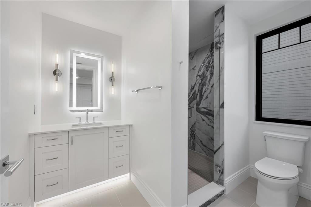 Bathroom featuring vanity, a marble finish shower, and light tile patterned floors