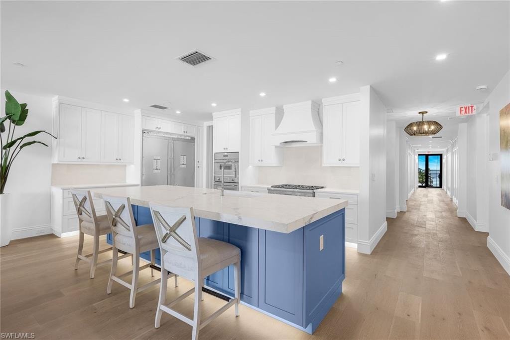 Kitchen with two tone cabinetry, an island with sink, a kitchen breakfast bar, recessed lighting, and built in refrigerator