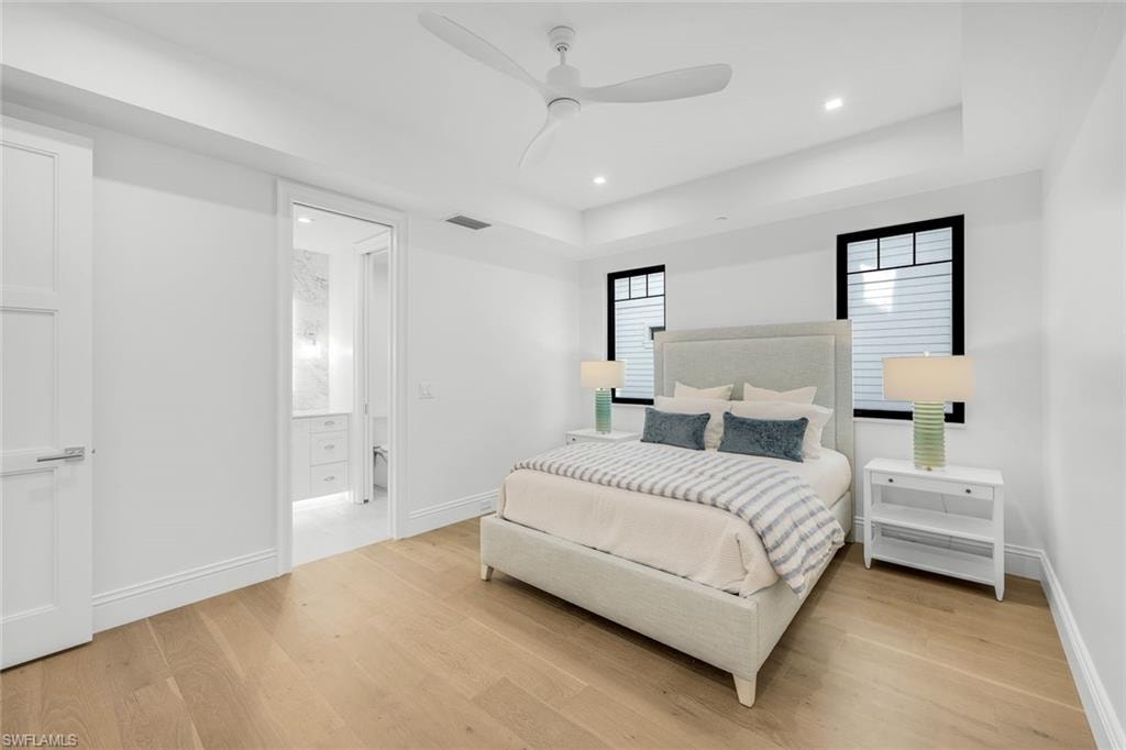 Bedroom featuring light wood-style floors, recessed lighting, ceiling fan, and a raised ceiling