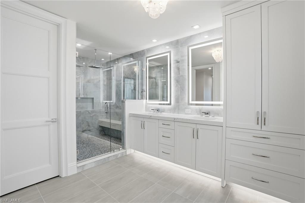 Bathroom with double vanity, a marble finish shower, light tile patterned floors, and recessed lighting