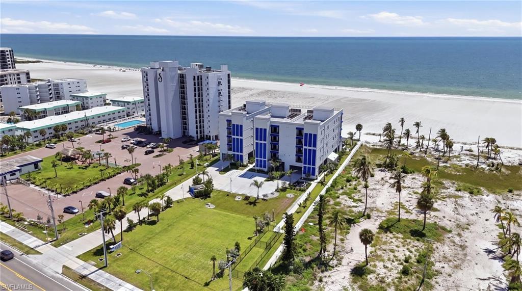 Coastal residential building with multiple balconies, adjacent to a wide sandy beach and ocean - Virtually Edited Image