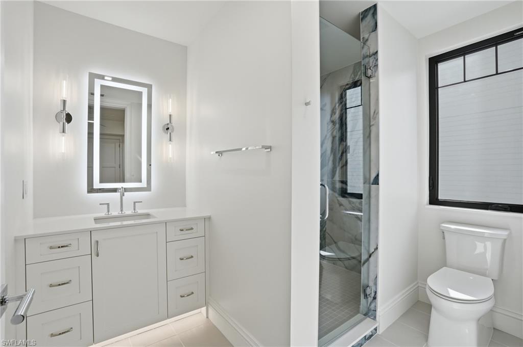 Full bath featuring vanity, a marble finish shower, and light tile patterned floors