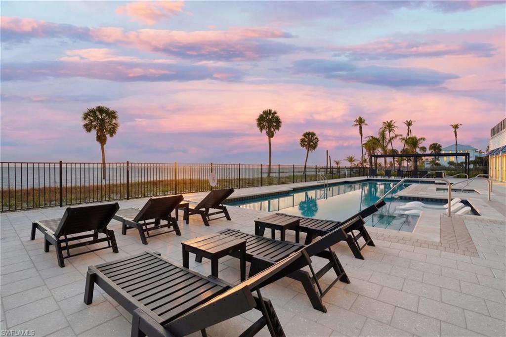 Pool at dusk featuring a patio and a community pool