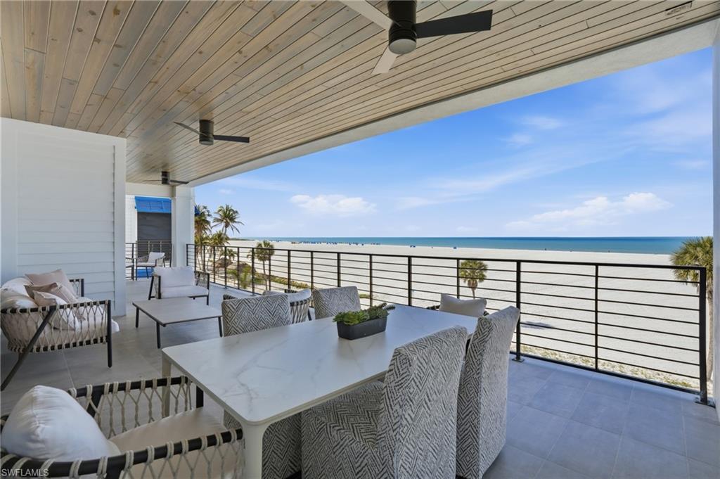Balcony with ceiling fan, view of water and beach, and outdoor lounge area