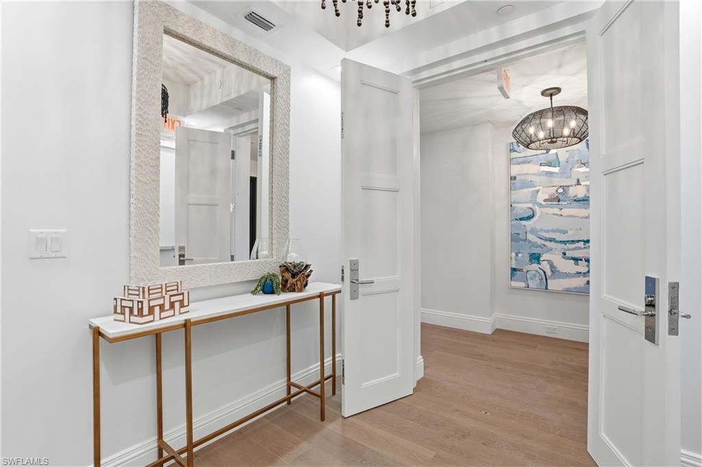 Hallway featuring light wood finished floors and a chandelier