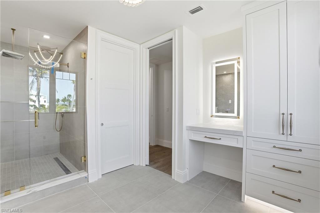 Full bathroom with vanity, light tile patterned floors, and a stall shower