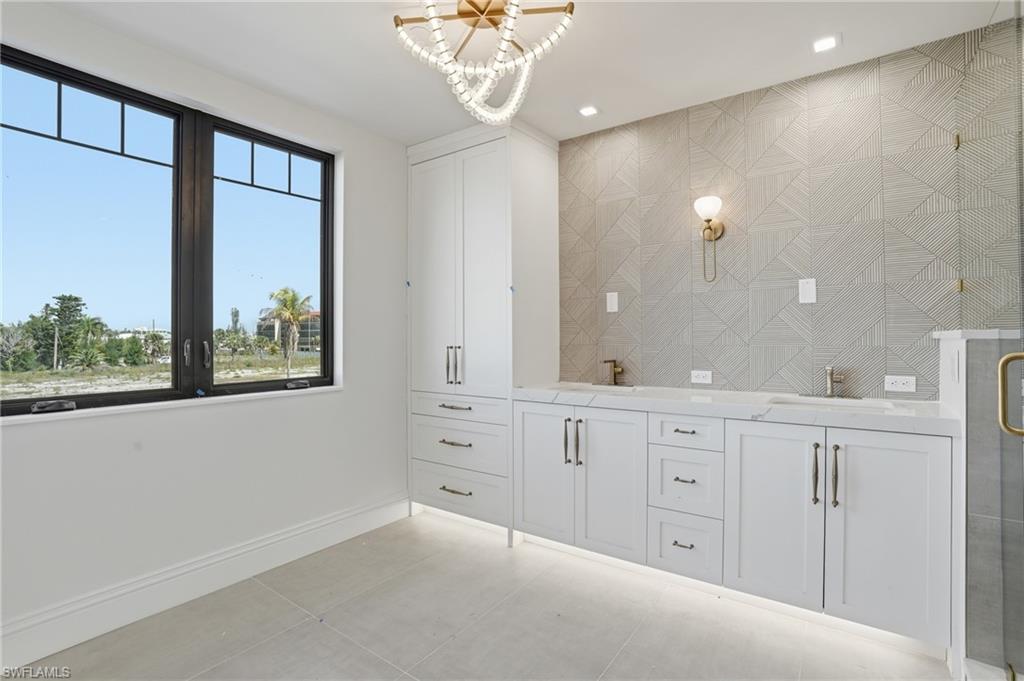 Bathroom with double vanity, hanging lights, a stall shower, and light tile patterned floors