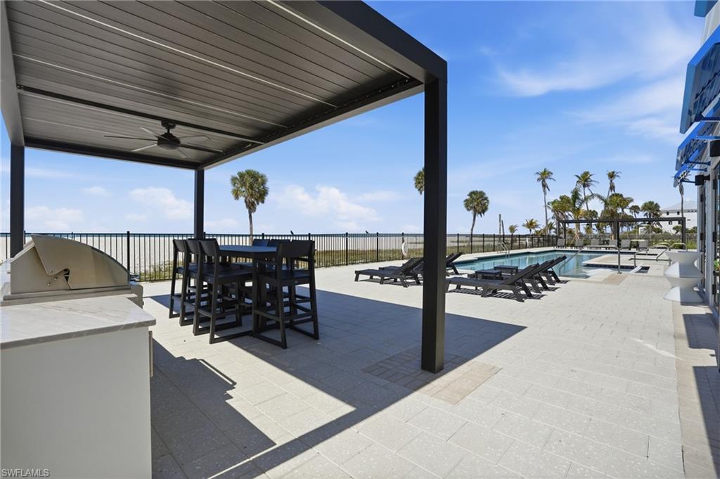View of patio / terrace featuring an outdoor kitchen / dining area, a ceiling fan, and a community pool