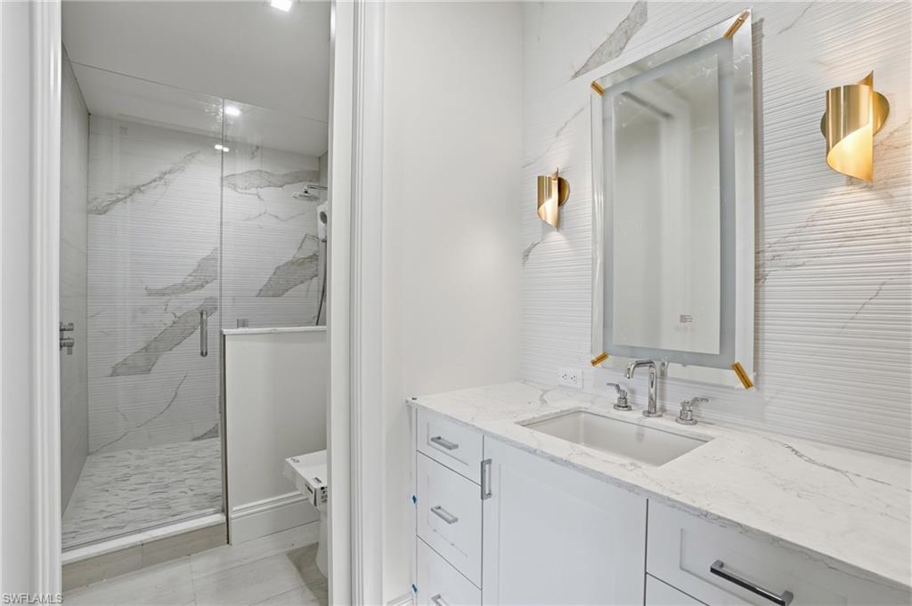 Full bathroom featuring vanity and a marble finish shower