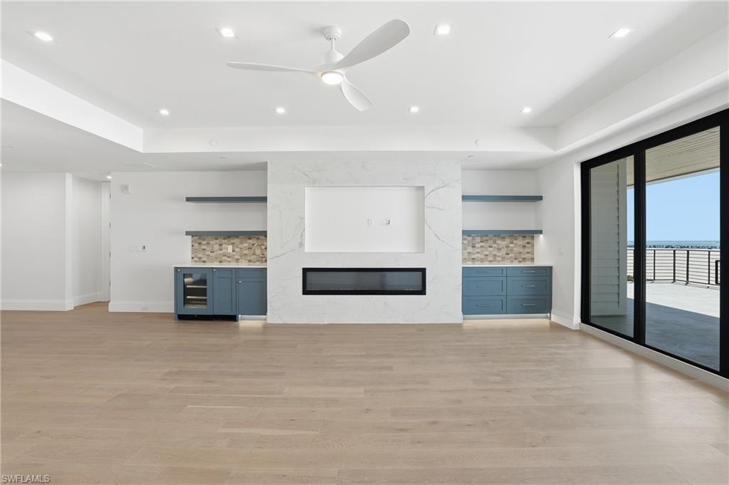 Unfurnished living room featuring light wood finished floors, a ceiling fan, a premium fireplace, and recessed lighting