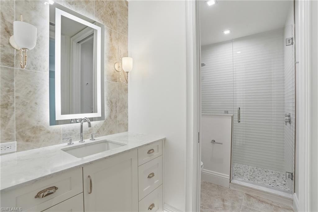 Full bath with vanity, a stall shower, tile walls, and recessed lighting