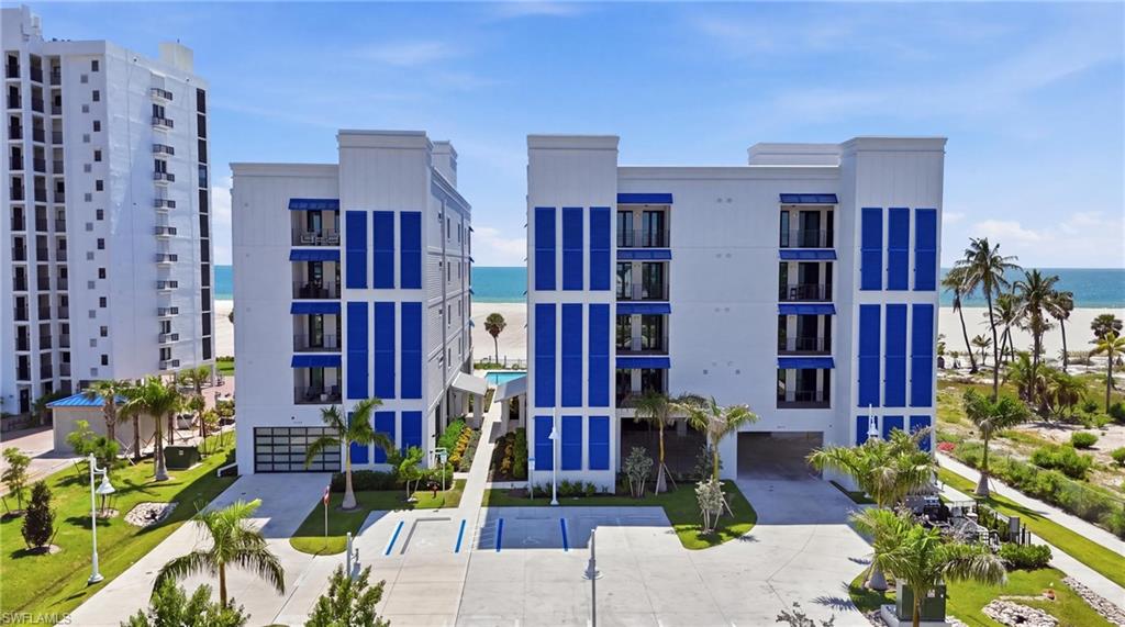 Contemporary architecture with blue accent panels, private balconies, a ground-level garage, and a lush, landscaped approach - Virtually Edited Image