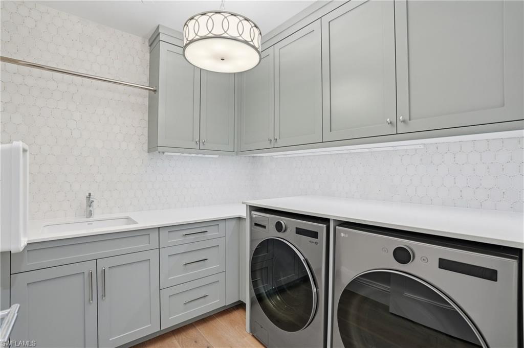 Laundry area with separate washer and dryer, light wood-style flooring, and cabinet space