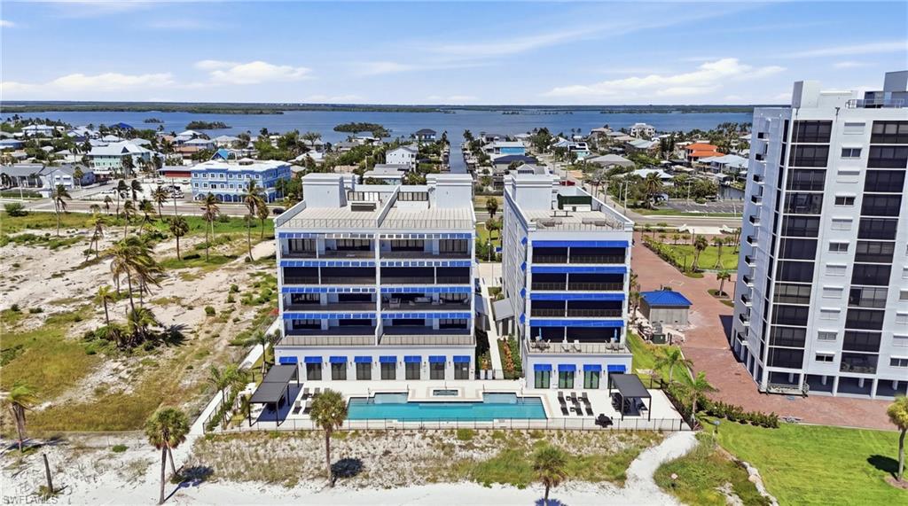 Waterfront apartment buildings featuring multiple balconies, a ground-level swimming pool, and dedicated poolside lounge areas - Virtually Edited Image