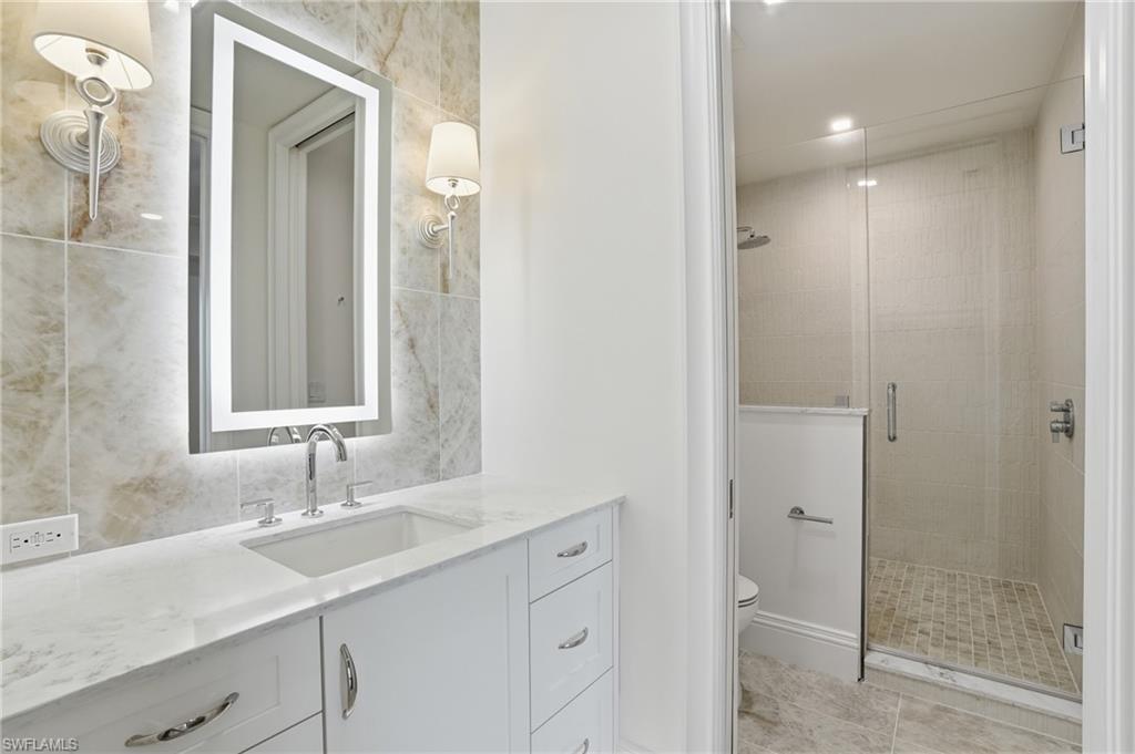 Full bath featuring vanity, a stall shower, and tile walls
