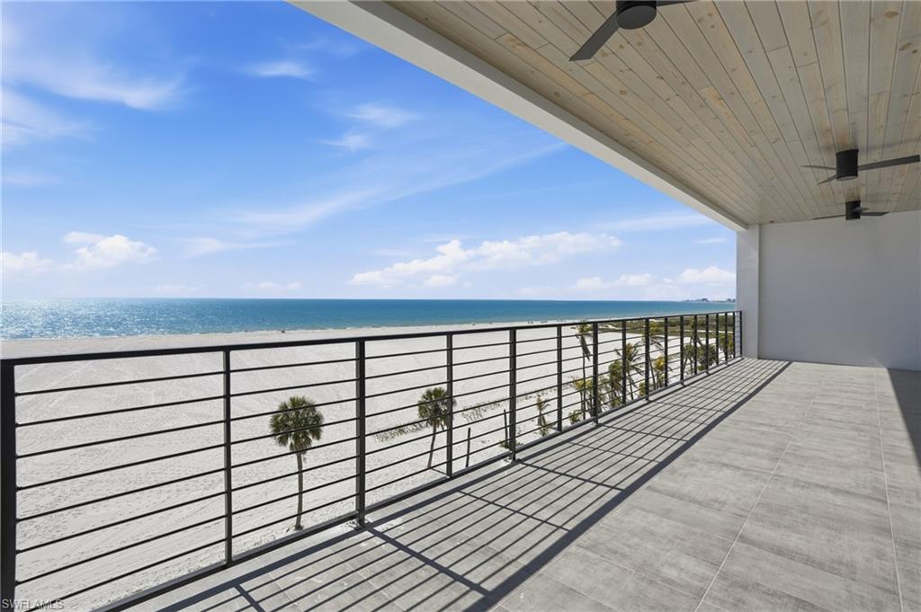 Balcony featuring a ceiling fan and view of water and beach