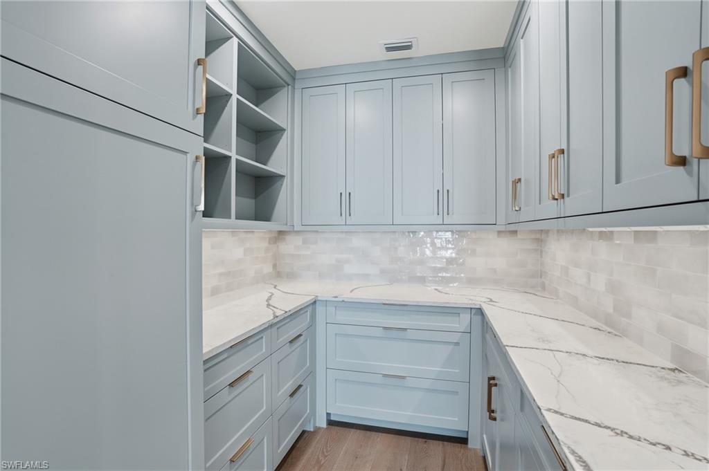Kitchen featuring light stone countertops, light wood finished floors, and tasteful backsplash