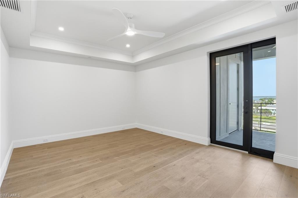 Unfurnished room featuring light wood-style floors, ceiling fan, crown molding, a tray ceiling, and recessed lighting