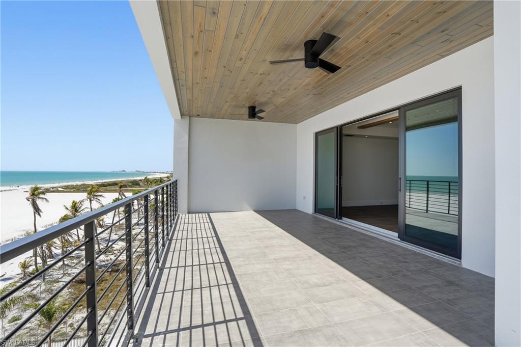 Balcony with view of water and beach and ceiling fan