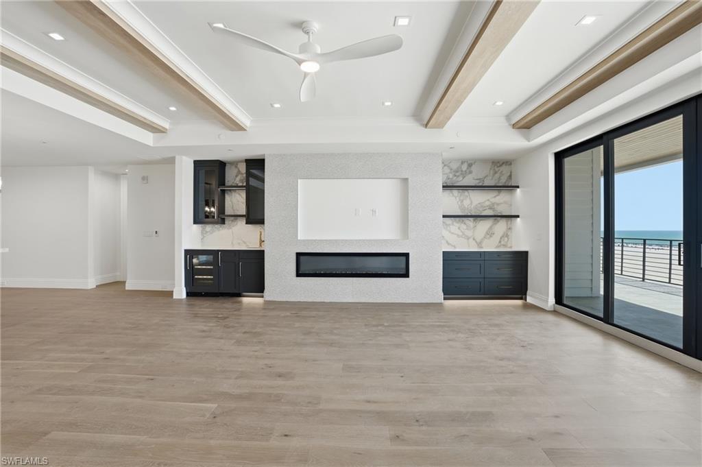 Unfurnished living room with a ceiling fan, recessed lighting, light wood-style flooring, an accent wall, and a glass covered fireplace
