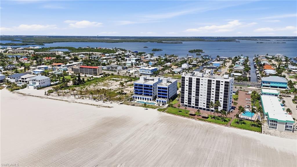 Waterfront property with direct beach access, featuring a swimming pool, adjacent parking area, and multi-story buildings - Virtually Edited Image