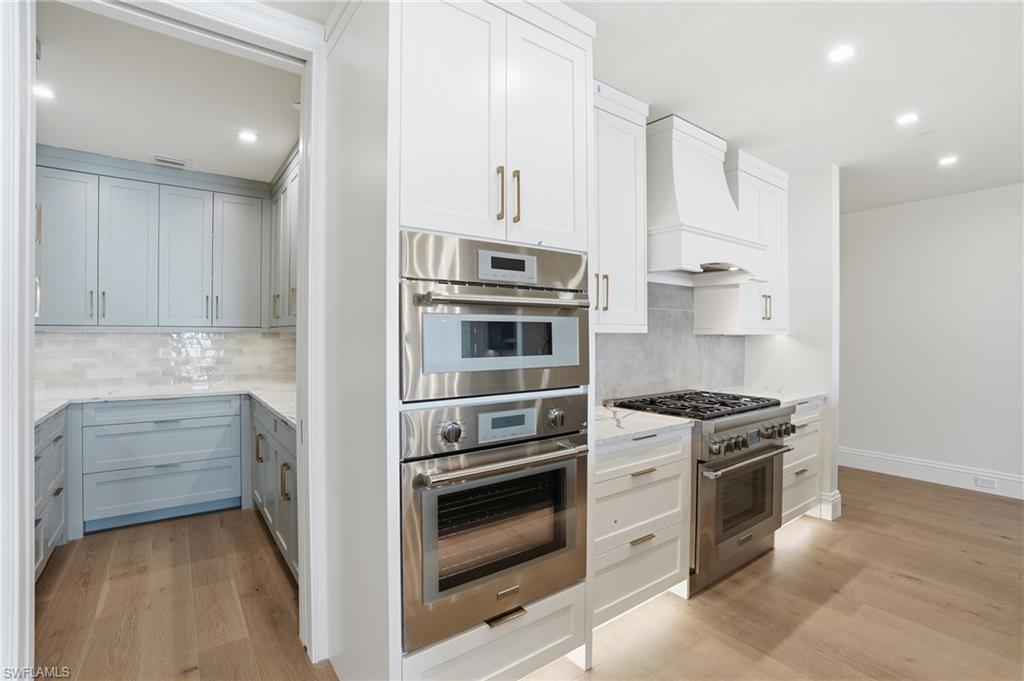 Kitchen featuring stainless steel appliances, light wood-style flooring, light stone countertops, recessed lighting, and decorative backsplash