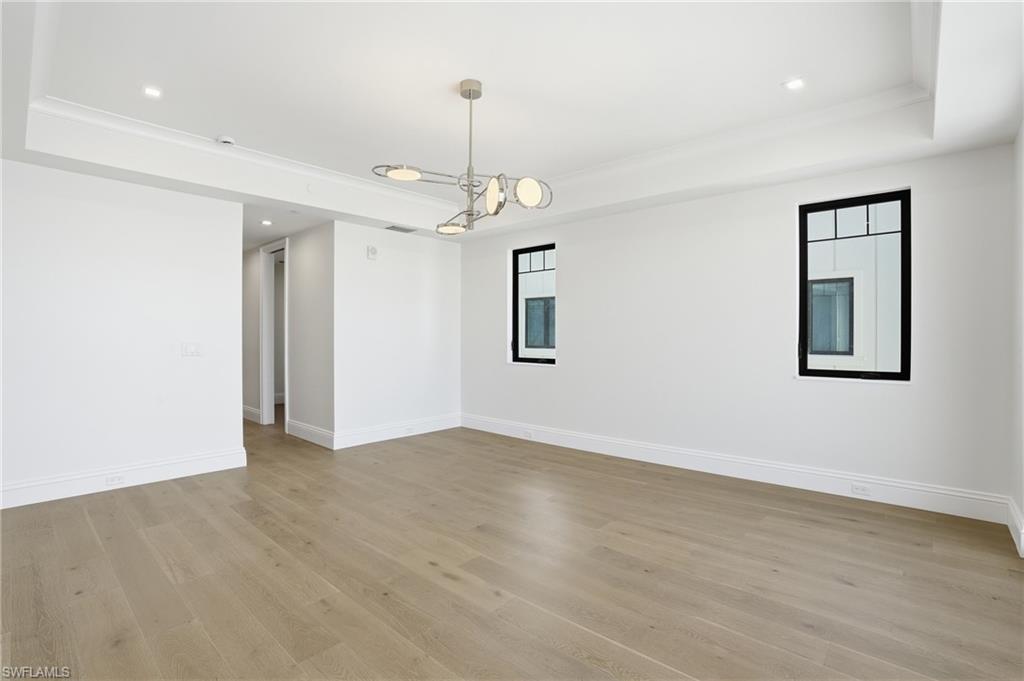Unfurnished room featuring a raised ceiling, recessed lighting, light wood finished floors, and ornamental molding
