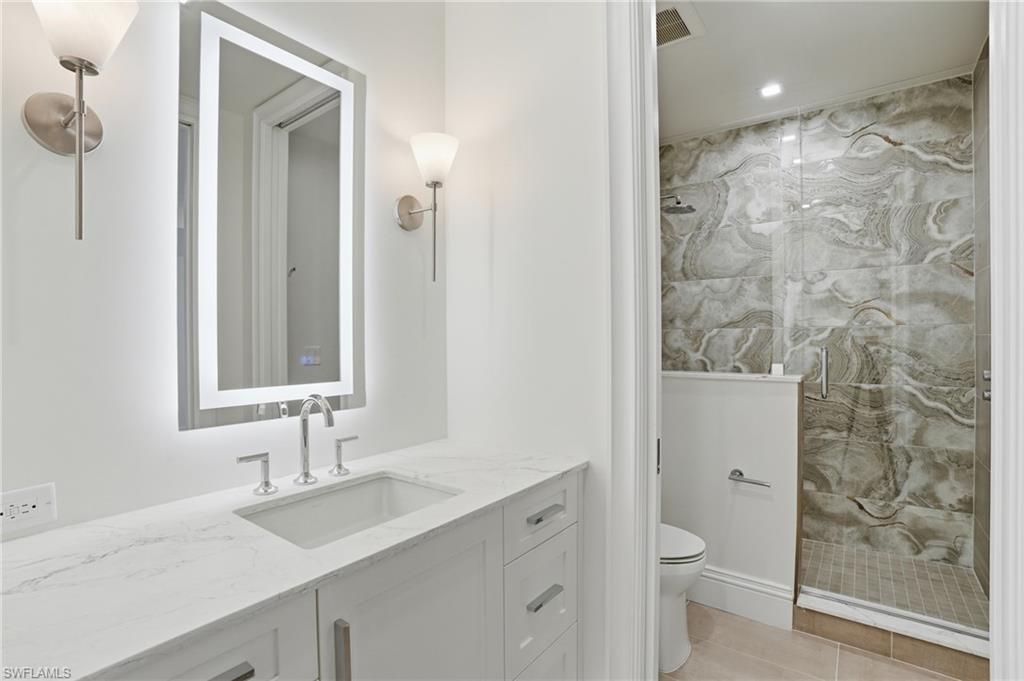 Bathroom featuring a marble finish shower, vanity, and recessed lighting