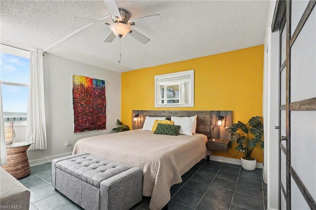 Bedroom featuring a textured ceiling, ceiling fan, and dark tile patterned flooring