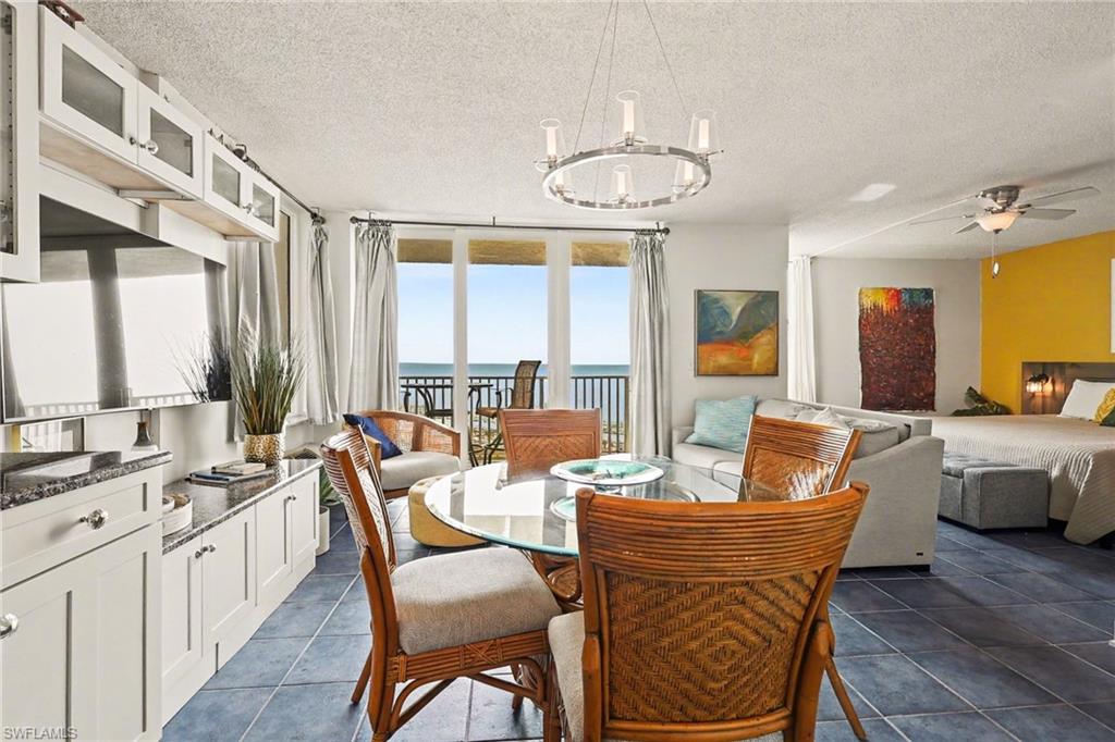 Dining space featuring a water view, a textured ceiling, a ceiling fan, and suspended lighting