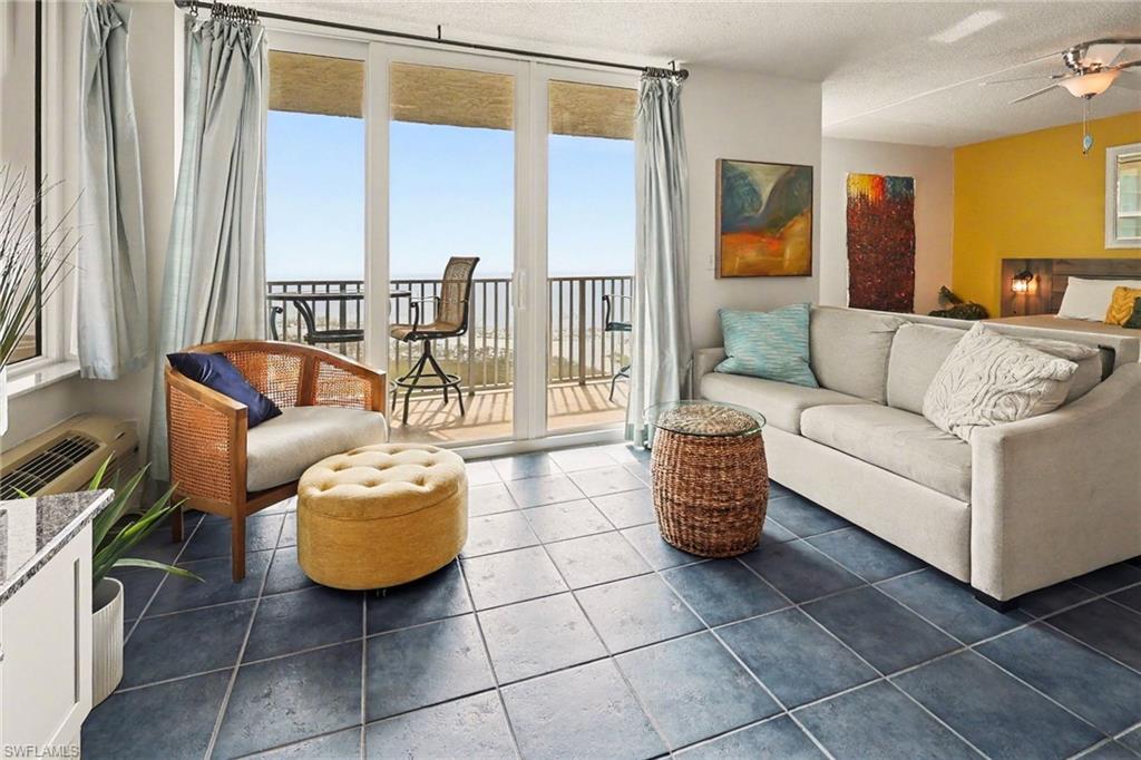 Living area featuring a ceiling fan, dark tile patterned floors, a textured ceiling, and expansive windows