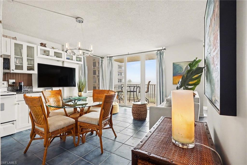 Dining space featuring a textured ceiling, dark tile patterned flooring, floor to ceiling windows, and a chandelier