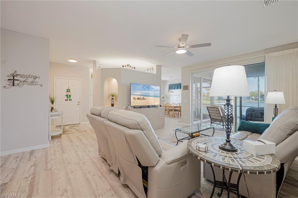 Living room featuring light wood-style flooring, a ceiling fan, and arched walkways