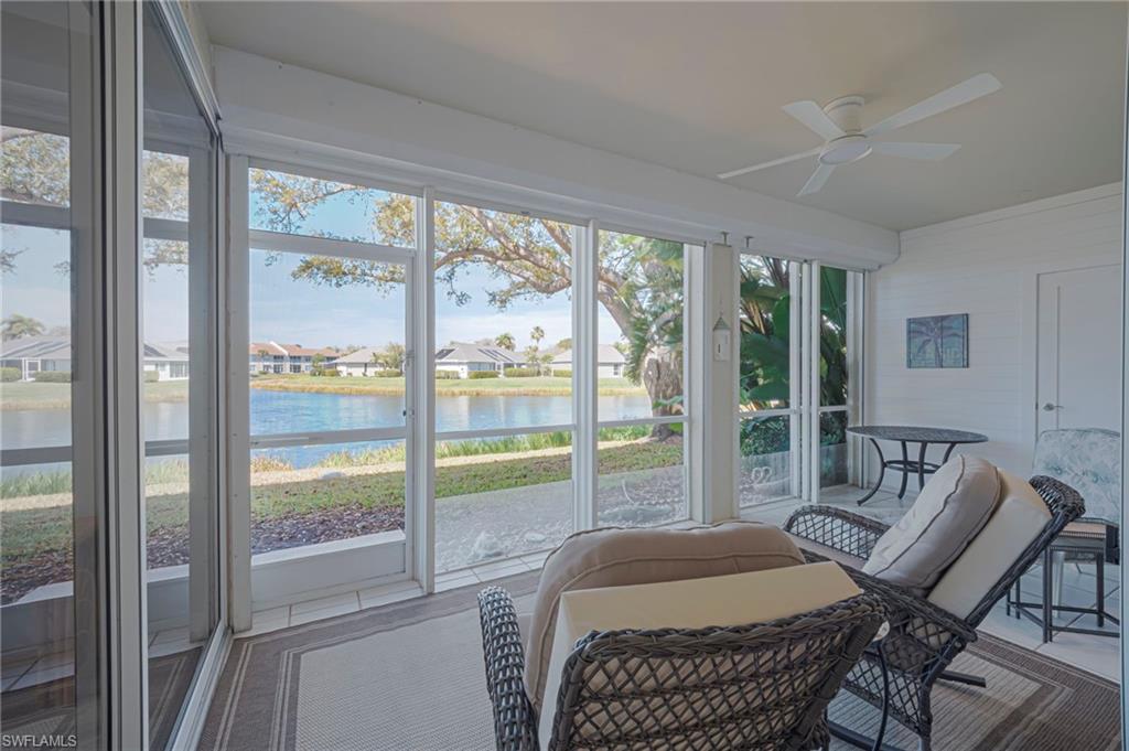 Sunroom featuring a ceiling fan, a residential view, and a water view