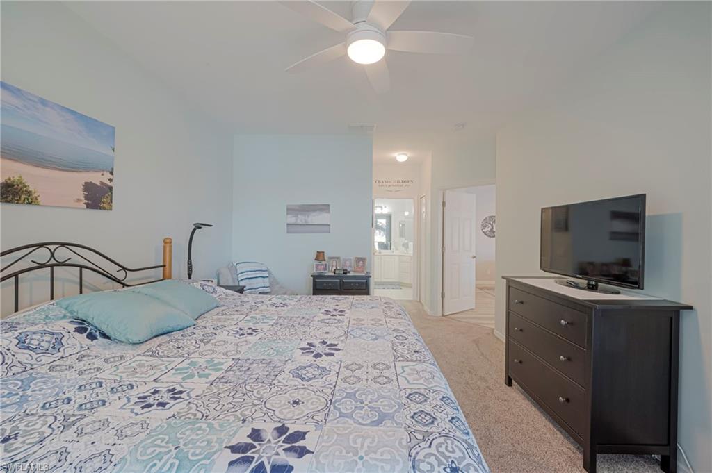 Bedroom with light colored carpet, a ceiling fan, and ensuite bath