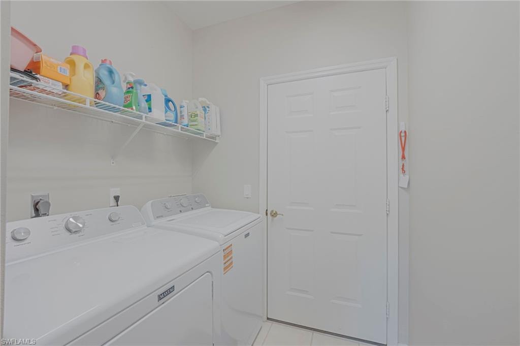 Laundry room with washer and clothes dryer and light tile patterned floors