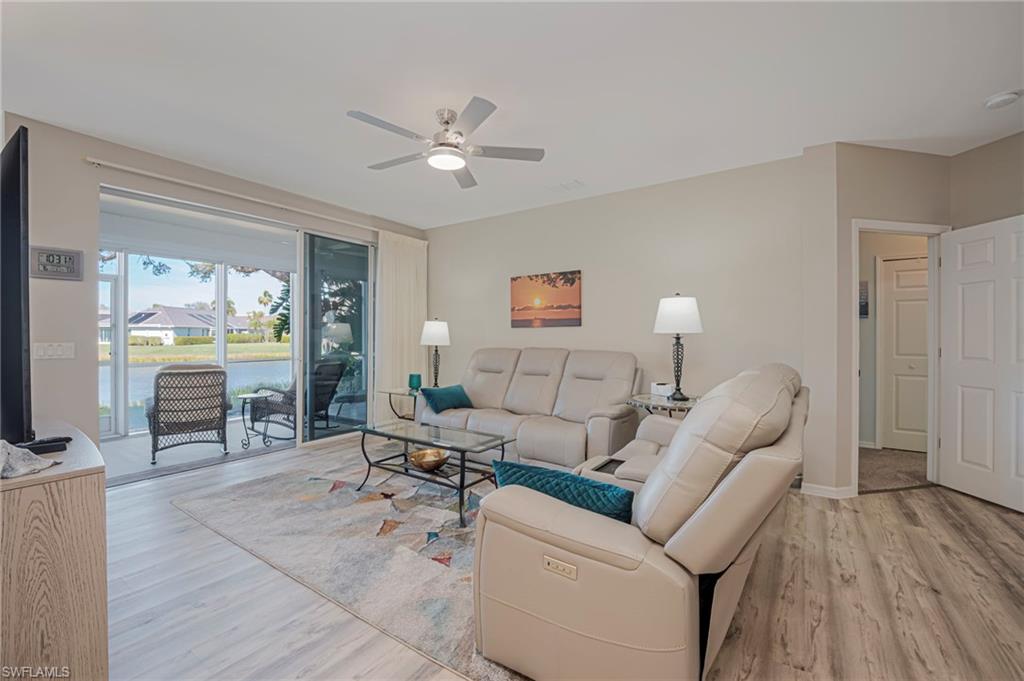 Living area featuring light wood-style flooring, ceiling fan, and a water view